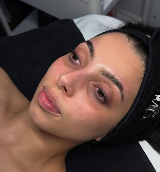 A person with a headband lies on a bed, showing freshly groomed eyebrows and clear skin under indoor lighting. - Jón Alan Salon in Nashville and Franklin, TN