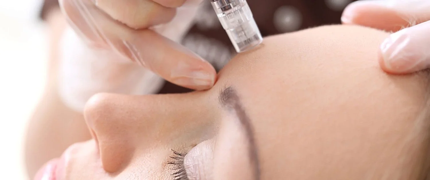A person receives a cosmetic injection in the forehead area while lying down, administered by someone wearing gloves, following a precision haircut with face-framing layers and blowout. - Jón Alan Salon in Nashville and Franklin, TN